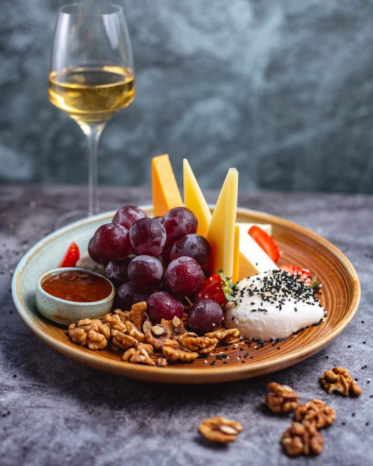 cheese-plate-with-walnuts-grapes-cheddar-goat-cheese-mozzarella-blue-cheese-strawberries-served-with-white-wine
